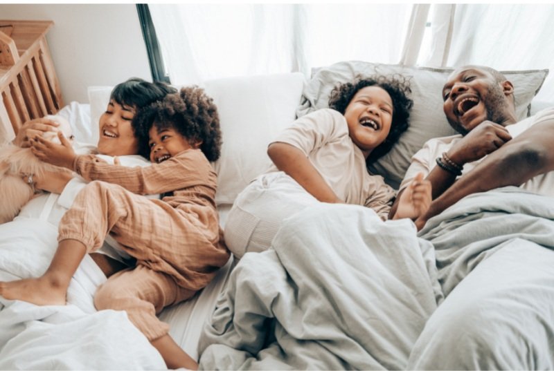 family laughing in bed - how to rollover a 401(k)
